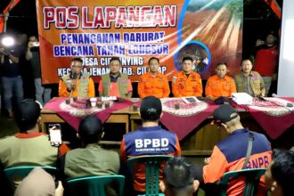 Deputi Bidang Penanganan Darurat BNPB, Mayjen TNI Budi Irawan (tengah) saat memimpin rapat koordinasi penanganan darurat bencana tanah longsor di Pos Lapangan Desa Cibeunying, Kecamatan Majenang, Kabupaten Cilacap, Jawa Tengah, Jumat (14/11/2025) malam. Foto: Ist