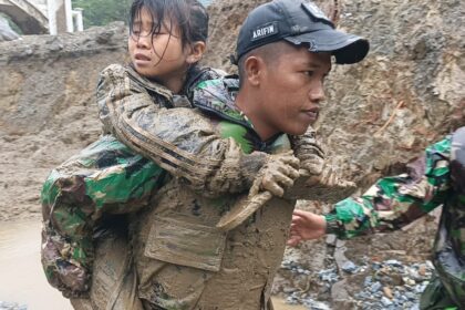 Salah seorang prajurit TNI AD tengah mengevakuasi seorang anak yang terdampak bencana di Kota Padang Panjang. Foto: Dispenad