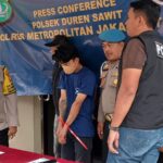 Penampakan pelaku berinisial RS alias EJA, 25, saat dikawal oleh penyidik ketika dihadirkan dalam konferensi pers pengungkapan kasus pencurian di Polsek Duren Sawit, Jakarta Timur, Jumat (28/11/2025) sore. Foto: Joesvicar Iqbal/ipol.id