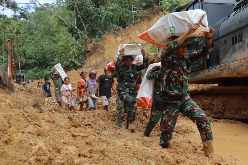 Prajurit tampak berjalan kaki sekitar lima kilometer untuk menyalurkan bantuan logistik ke Desa Naga Timbul, Desa Mompang, dan Desa Mardame setelah akses jalan menuju wilayah tersebut terputus total. Foto: Dispenad