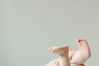 Ilustrasi, Bayi berbaring telentang dengan tangan dan kaki di udara. Foto: Istock @SDVincent