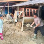 Personel Posko 1 Batalyon C Pelopor Sat Brimob Polda Sumatera Utara membantu membersihkan lumpur tebal yang menutupi pekarangan rumah warga di Desa Aek Ngadol, Kecamatan Batang Toru, Jumat (12/12/2025). Foto: Ist