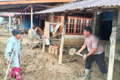 Personel Posko 1 Batalyon C Pelopor Sat Brimob Polda Sumatera Utara membantu membersihkan lumpur tebal yang menutupi pekarangan rumah warga di Desa Aek Ngadol, Kecamatan Batang Toru, Jumat (12/12/2025). Foto: Ist