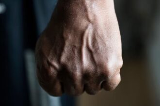 Ilustrasi - Seorang pria yang emosional mengepalkan jemari tangan dengan erat dan siap untuk meninju musuhnya. Foto: Freepik