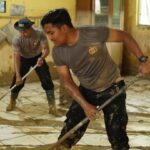 Sejumlah personel Polres Langsa bersama masyarakat melakukan gotong royong membersihkan lingkungan sekolah terdampak banjir di Wilayah Kabupaten Aceh Tamiang, Kamis (25/12/2025). Foto: Ist