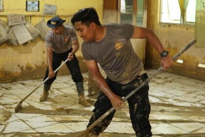 Sejumlah personel Polres Langsa bersama masyarakat melakukan gotong royong membersihkan lingkungan sekolah terdampak banjir di Wilayah Kabupaten Aceh Tamiang, Kamis (25/12/2025). Foto: Ist