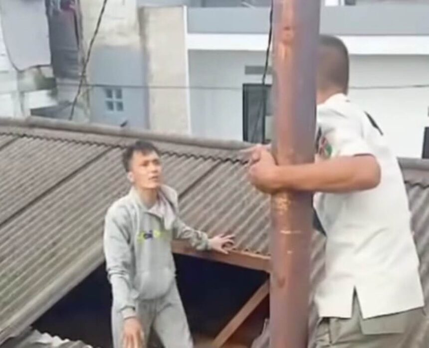 Petugas Satpol PP Kecamatan Pancoran, berupaya mengamankan pria terduga pencuri yang naik ke atap rumah warga di Jalan Pancoran Barat VIII, Pancoran, Jakarta Selatan, Minggu (4/1/2026) siang. Foto: Tangkapan layar Instagram @sekitar_jaksel