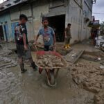 Suasana warga sekitar bergotong royong mengangkut lumpur menyumbat drainase di Jalan Raya Rantau, Bukit Tempurung, Kota Kuala Simpang, Kabupaten Aceh Tamiang, Jumat (9/1/2026). Foto: Ist