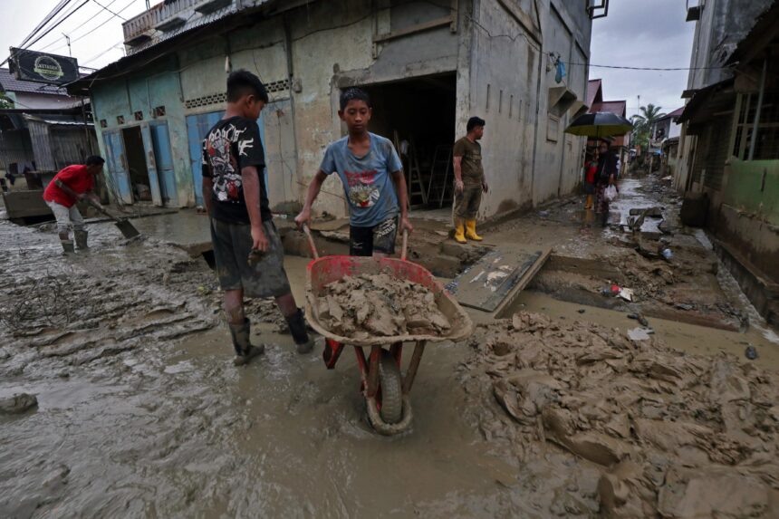 Suasana warga sekitar bergotong royong mengangkut lumpur menyumbat drainase di Jalan Raya Rantau, Bukit Tempurung, Kota Kuala Simpang, Kabupaten Aceh Tamiang, Jumat (9/1/2026). Foto: Ist
