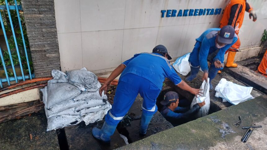 Sejumlah Pasukan Biru Sudin Sumber Daya Air (SDA) Jakarta Selatan, saat membersihkan saluran air yang tersumbat sampah dan lumpur dalam aksi kerja bakti serentak di kawasan Jalan Kapten Tendean, Kebayoran Baru, Jakarta Selatan, Selasa (13/1/2026) pagi. Foto: Joesvicar Iqbal/ipol.id