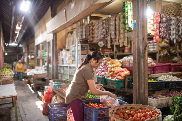 Ilustrasi, seorang pedagang sayur melayani pembeli di pasar Indonesia. Foto: Istcok @primeimages