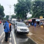 Kondisi arus lalu lintas yang macet mengular di Jalan Raya Bogor, Kramat Jati, Jakarta Timur, mengarah traffick light Pusat Grosir Cililitan (PGC), Senin (12/1/2026) siang. Sejumlah kendaraan berupaya menghindari genangan. Foto: Joesvicar Iqbal/ipol.id