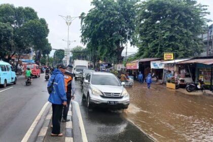 Kondisi arus lalu lintas yang macet mengular di Jalan Raya Bogor, Kramat Jati, Jakarta Timur, mengarah traffick light Pusat Grosir Cililitan (PGC), Senin (12/1/2026) siang. Sejumlah kendaraan berupaya menghindari genangan. Foto: Joesvicar Iqbal/ipol.id
