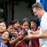 Pelatih Kepala MilkLife Soccer Challenge Timo Scheunemann saat memberikan tanda tangan kepada para peserta MLSC Bandung Seri 2 2025 - 2026. Foto/Megapro