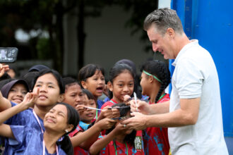 Pelatih Kepala MilkLife Soccer Challenge Timo Scheunemann saat memberikan tanda tangan kepada para peserta MLSC Bandung Seri 2 2025 - 2026. Foto/Megapro