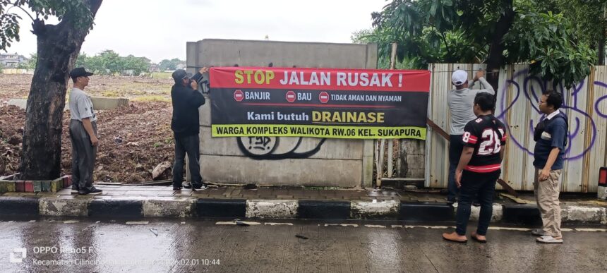 Warga membentangkan spanduk bertuliskan protes terhadap pengurukan lahan.(foto sofian/ipol.id).