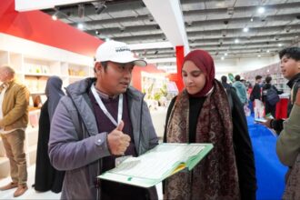 Petugas Kemenag menjelaskan Mushaf Alquran Isyarat pertama di dunia kepada pengunjung booth Indonesia. Foto: Kemenag