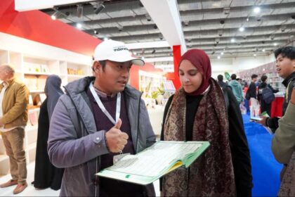 Petugas Kemenag menjelaskan Mushaf Alquran Isyarat pertama di dunia kepada pengunjung booth Indonesia. Foto: Kemenag