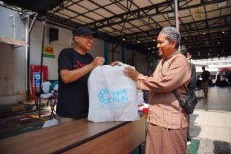 Tampak personel Yayasan Baitul Maal PLN menyerahkan sedekah daging kepada penerima manfaat, salah satu pengurus panti asuhan di Surabaya. Foto: Dok PLN
