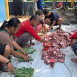 Para jurnalis tergabung di kelompok kerja Jurnalis Jakarta Utara membungkus daging kurban menggunakan daun pisang untuk dibagikan ke warga di kawasan Ancol, Pademangan, Jakarta Utara, Rabu (27/5/2026). Foto: Ist