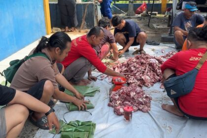 Para jurnalis tergabung di kelompok kerja Jurnalis Jakarta Utara membungkus daging kurban menggunakan daun pisang untuk dibagikan ke warga di kawasan Ancol, Pademangan, Jakarta Utara, Rabu (27/5/2026). Foto: Ist