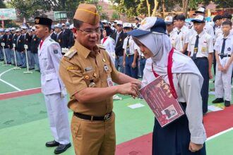 Wali Kota Jakarta Selatan, Syafrin Liputo menyematkan tanda pengenal Masa Pengenalan Lingkungan Sekolah (MPLS) kepada perwakilan siswa sebagai simbol dimulainya rangkaian kegiatan pengenalan lingkungan sekolah Tahun Ajaran 2026/2027 di SMKN 57 Jakarta, Jalan Margasatwa Raya, Ragunan, Pasar Minggu, Senin (13/7/2026) pagi. Foto: Ist